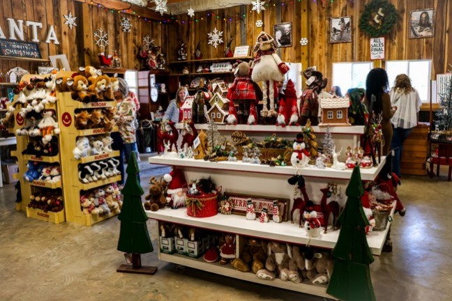 Festive holiday store display with stuffed animals, Christmas decorations, and shoppers browsing.